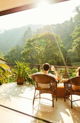 Rear view of a couple relaxing in the chairs at hotel balcony